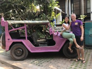 Sreyneang and John Ganshaw posing next to a lavender colored jeep in front of the Butterfly Pea Hotel